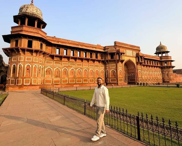 Viajero en el césped frente al palacio de arenisca roja Jahangiri Mahal, en el Fuerte de Agra, India