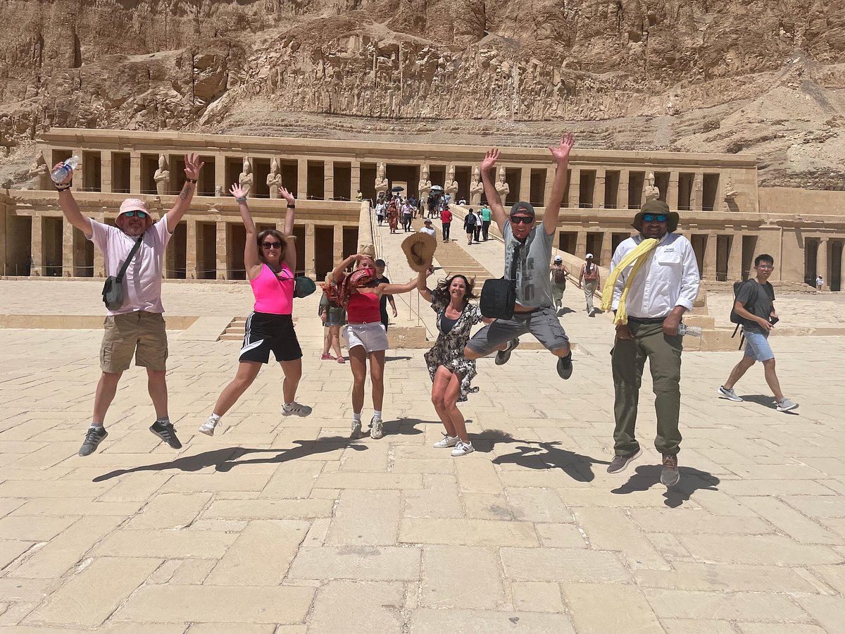Viajeros felices saltando frente al Templo de Hatshepsut en Luxor